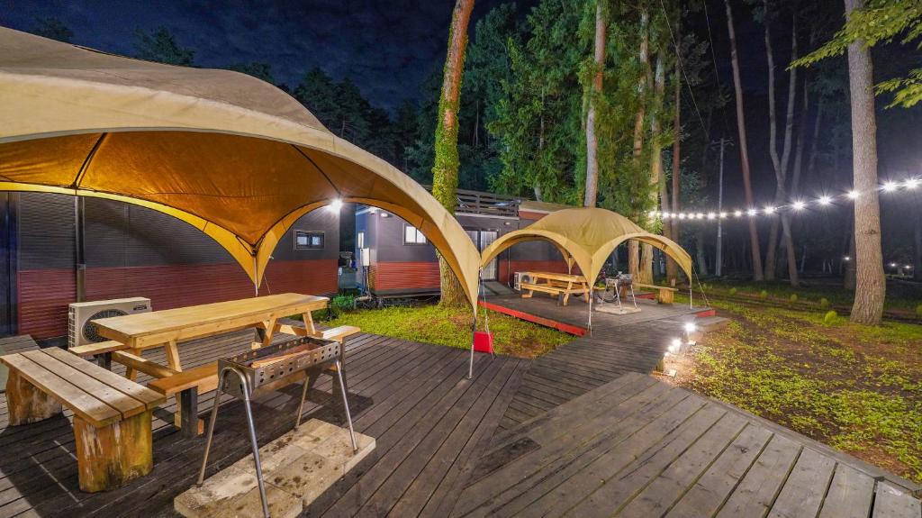 een terras met twee tenten en een tafel en banken bij 森と湖の楽園ＷorkshopＣampＲesort in Fujikawaguchiko