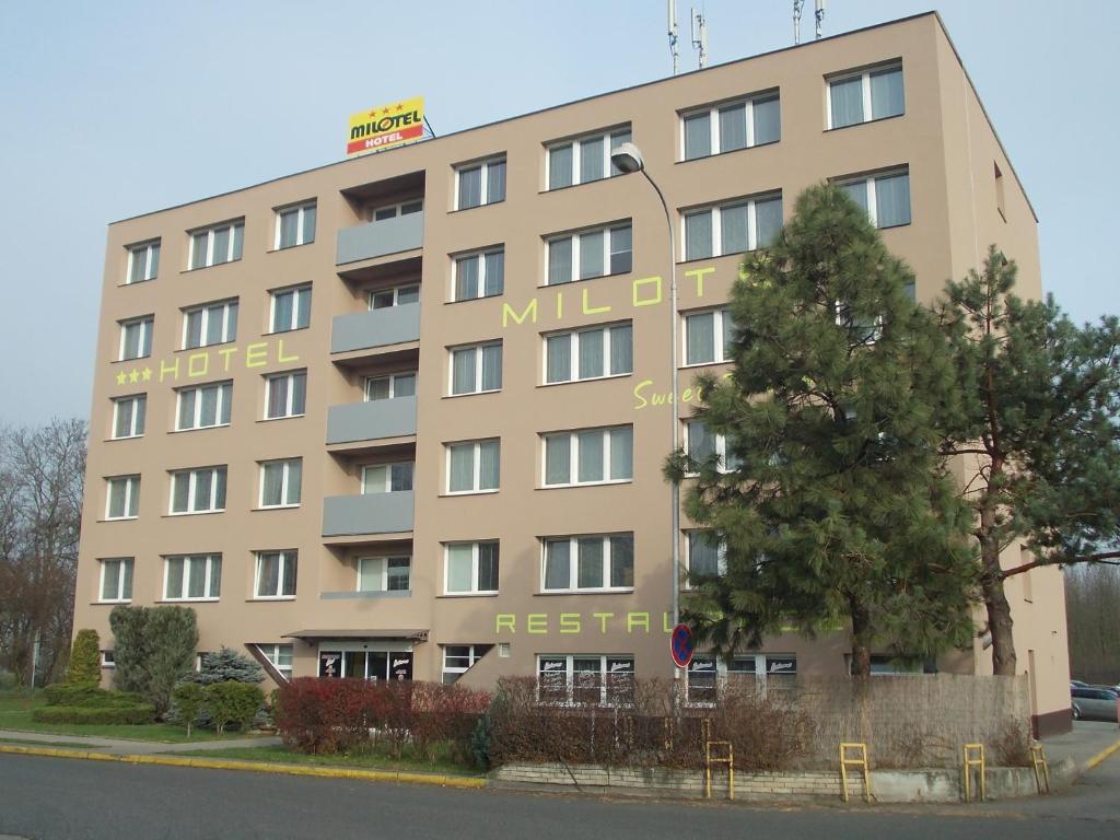 un edificio bronceado con un árbol delante de él en Hotel Milotel en Olomouc