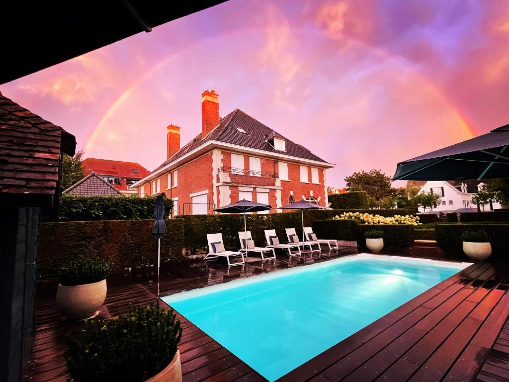 una piscina frente a una casa con arco iris en Romantik B&B Zonnehuis, en De Haan