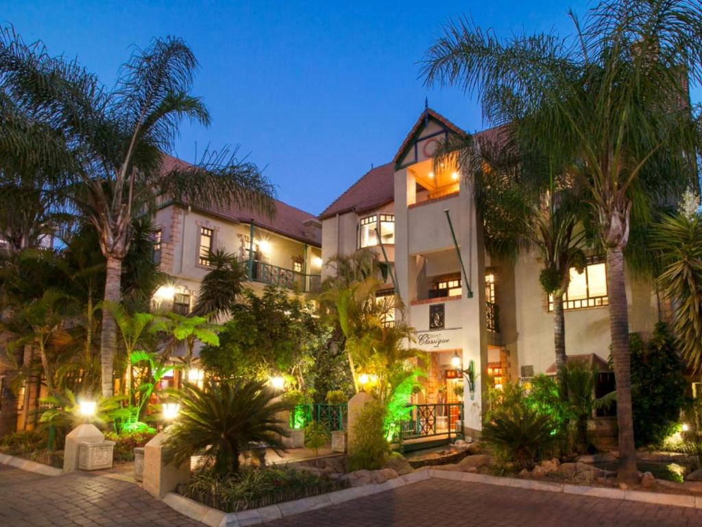een hotel met palmbomen en 's nachts verlichting bij Court Classique Suite Hotel in Pretoria