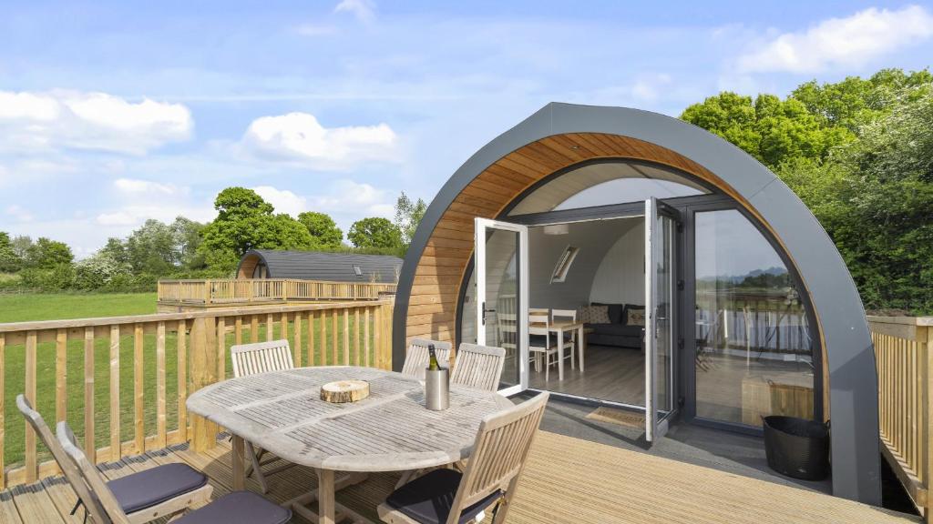 a pod house with a table and chairs on a deck at Finest Retreats - The Chicken Coop in Hertford