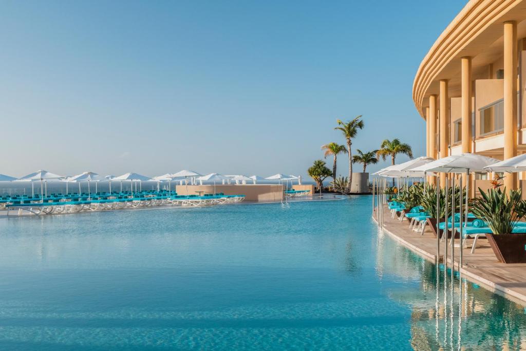 a pool at a resort with chairs and umbrellas at Iberostar Selection Fuerteventura Palace in Morro del Jable