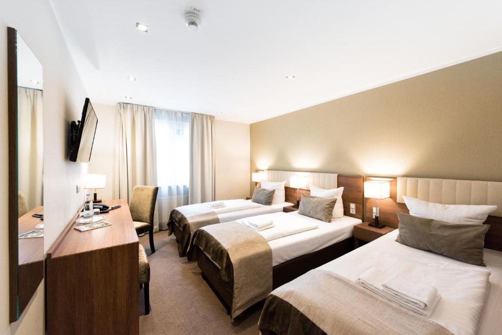 a hotel room with two beds and a desk at Arena am Zoo in Frankfurt