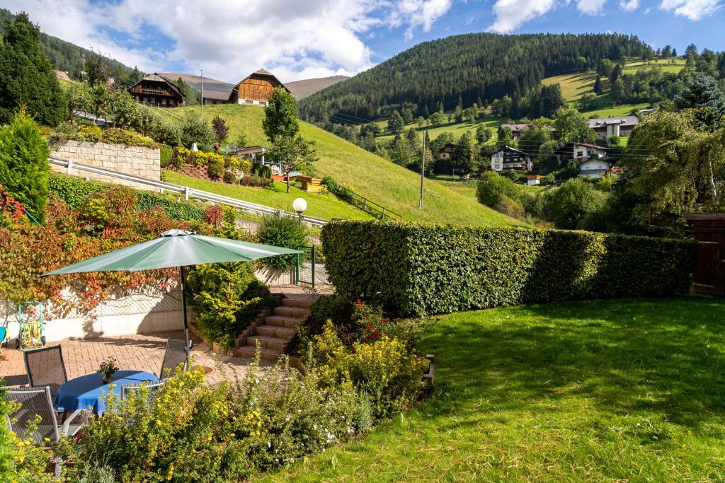 a garden with an umbrella and a hill at Heimeliges Apartment in den Bergen in Bad Kleinkirchheim