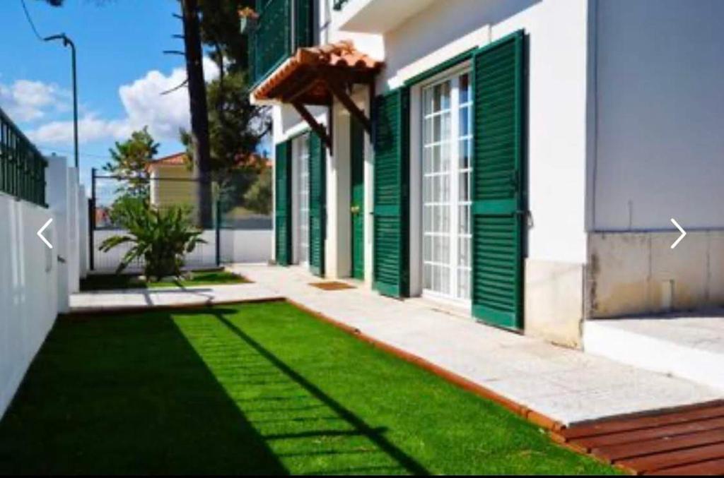 a house with green doors and a yard with grass at Azeitao Idílica Moradia T4 no Descanso do Campo in Setúbal
