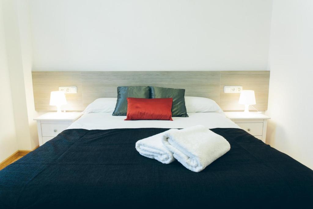 a bedroom with a large bed with two towels on it at The Lucky Flats - Artilleros in Alicante