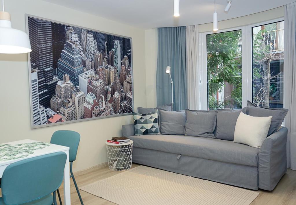 un salon avec un canapé gris et un tableau dans l'établissement ~ The Blue Apartment ~ 1BD with a Cozy Balcony, à Varna