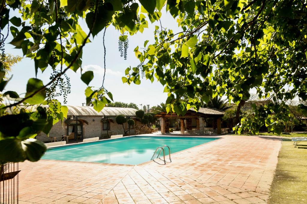 a swimming pool with a brick patio and trees at Agriturismo Posta Guevara in Castelluccio dei Sauri