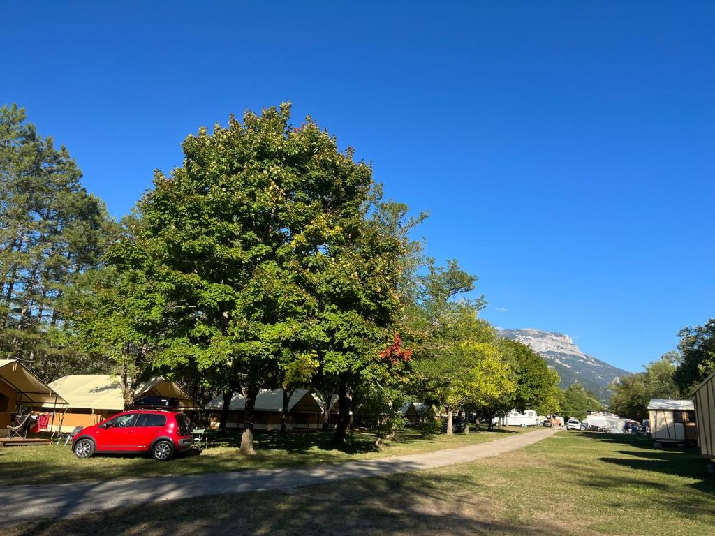 a red car parked next to a tree at CAMPING ONLYCAMP CHAMARGES in Die