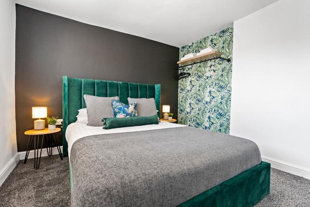 a bedroom with a large bed with a green headboard at The Treehouse at The Hideaway STAMP SA in Blackpool