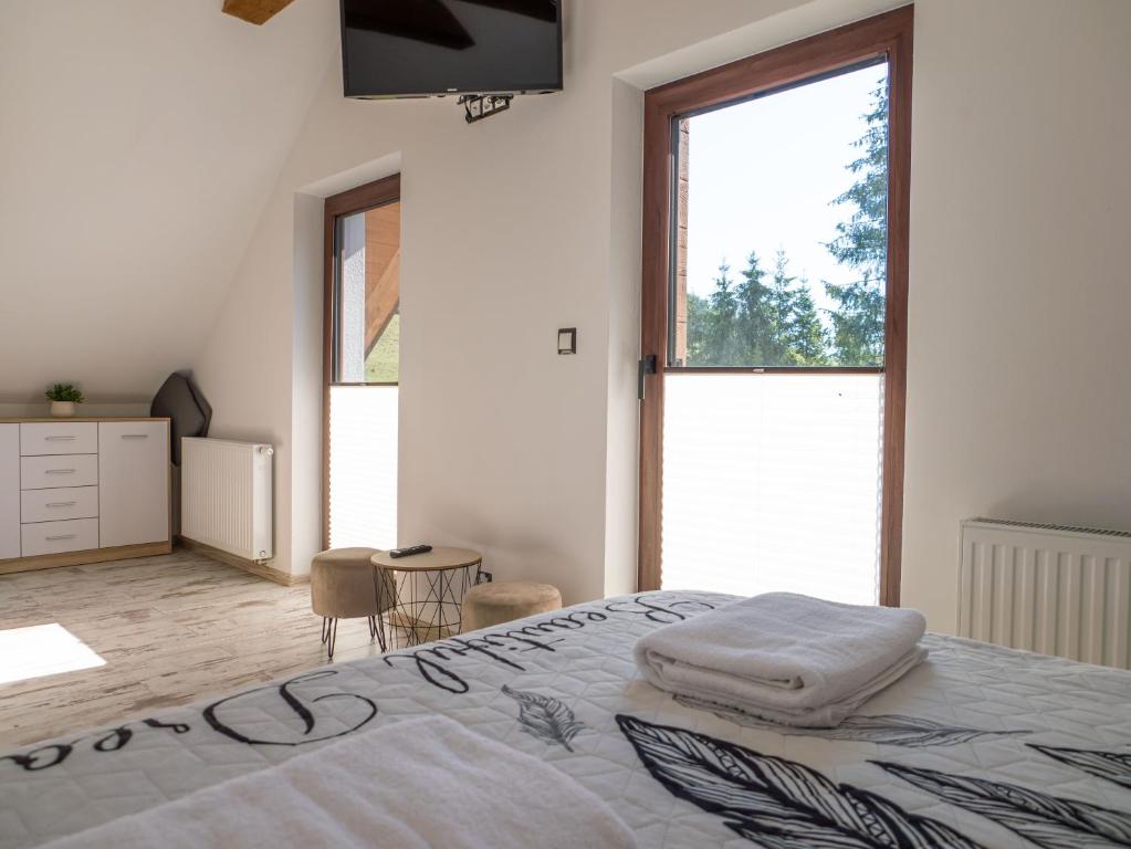 a white bedroom with a bed and a television at Domki nad potokiem in Muszynka