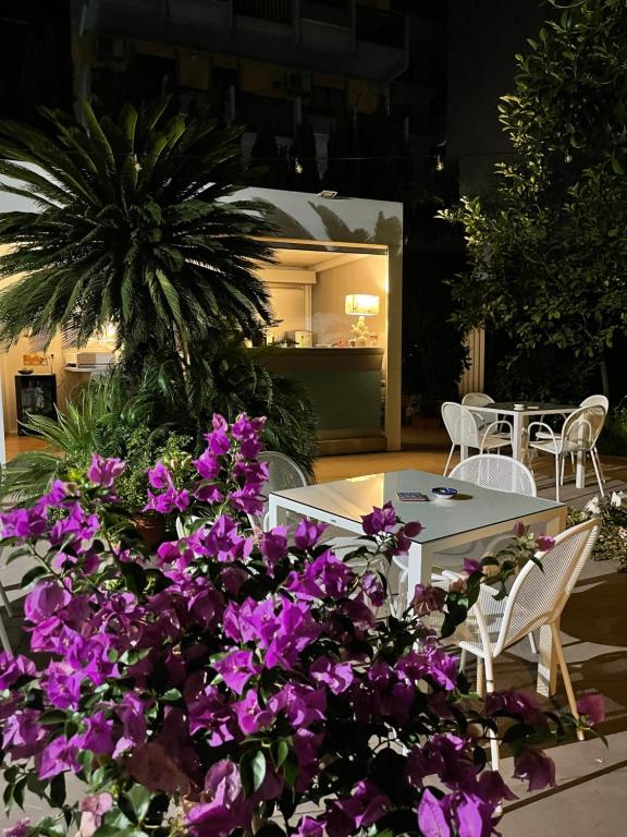 un patio con flores púrpuras, mesa y sillas en Liddo Boutique hotel, en Barletta