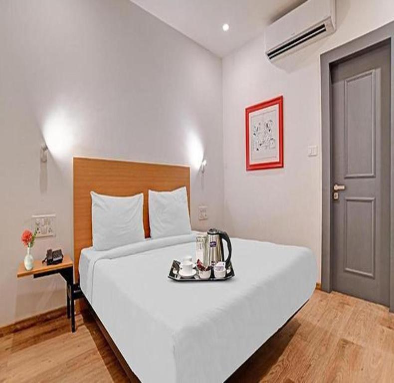 Un dormitorio con una gran cama blanca y una bandeja. en FabHotel Destiny 78, en Indore