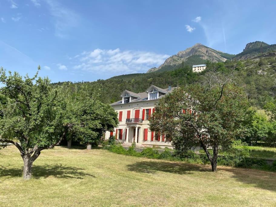 a large house with trees in front of a mountain at Magnifique appartement 8 couchages dans villa historique in Jausiers