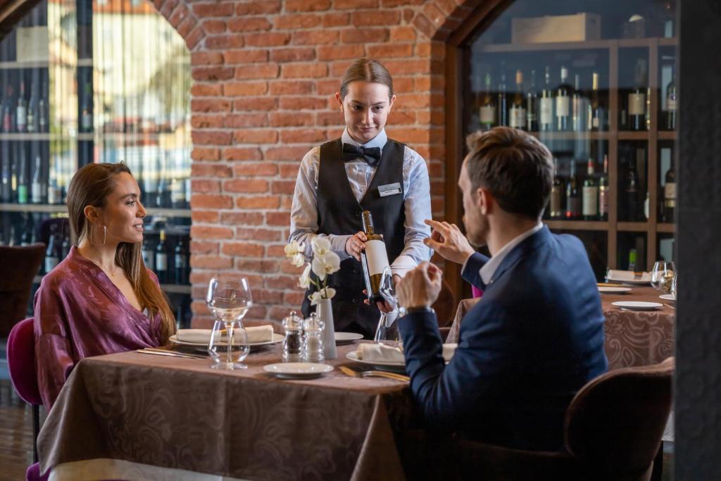 a waiter serving people at a table in a restaurant at Hotel Kaj in Marija Bistrica