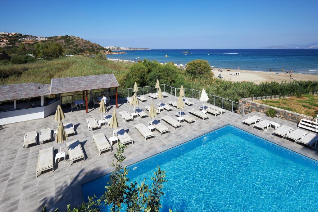 basen z krzesłami i widokiem na plażę w obiekcie Blu Acqua Hotel w mieście Ajos Nikolaos