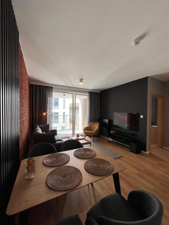 a living room with a table and a tv at Apartamenty BRUNO i BIANCA w Symphony Modern Tower Gdynia 2 i 3 piętro in Gdynia
