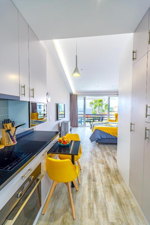 a kitchen with a table and yellow chairs in a room at Vista Oceano III in Caniço