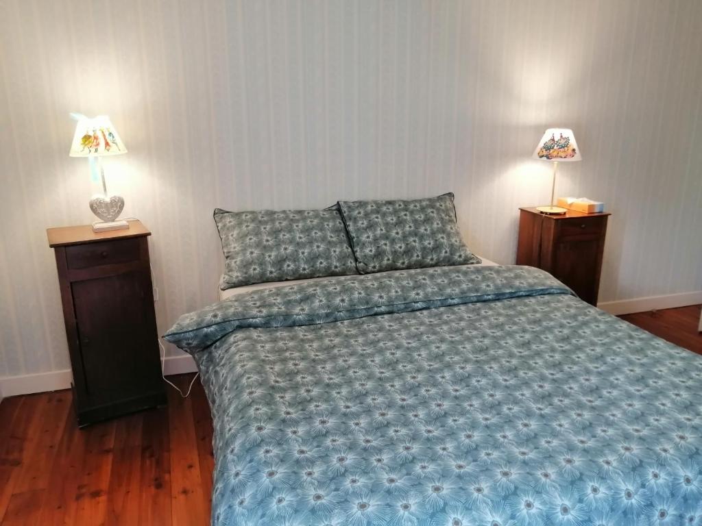 a bedroom with a bed with a blue comforter and two lamps at LE RELAIS DE LA FONTAINE in Échandelys