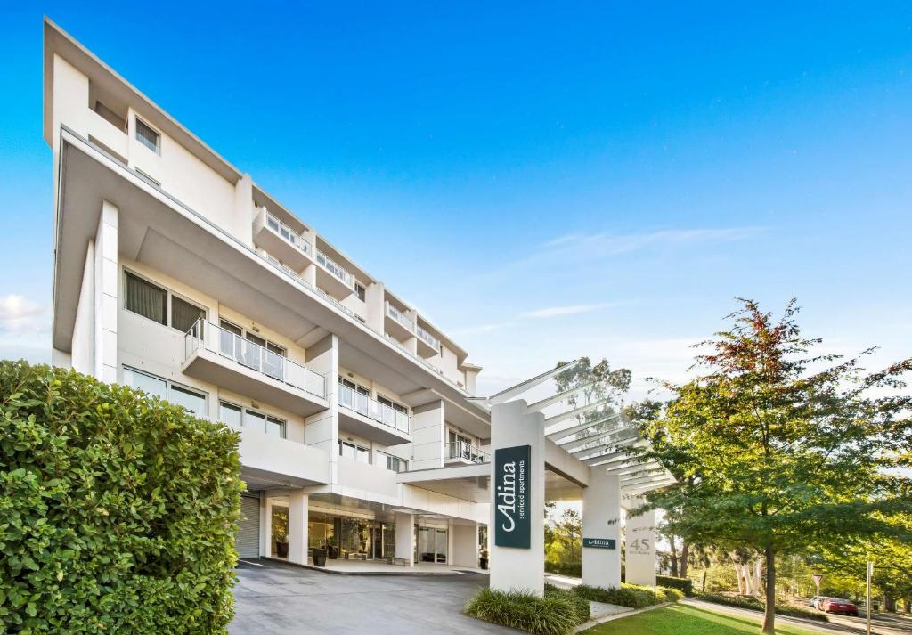 an exterior view of a white apartment building at Adina Serviced Apartments Canberra Dickson in Canberra