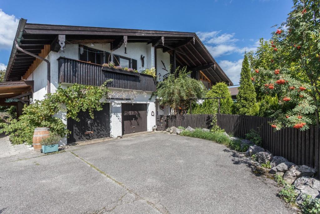 ein weißes Haus mit einem Zaun und einer Einfahrt in der Unterkunft Zwischen Chiemsee und Bergen Dg in Bernau am Chiemsee