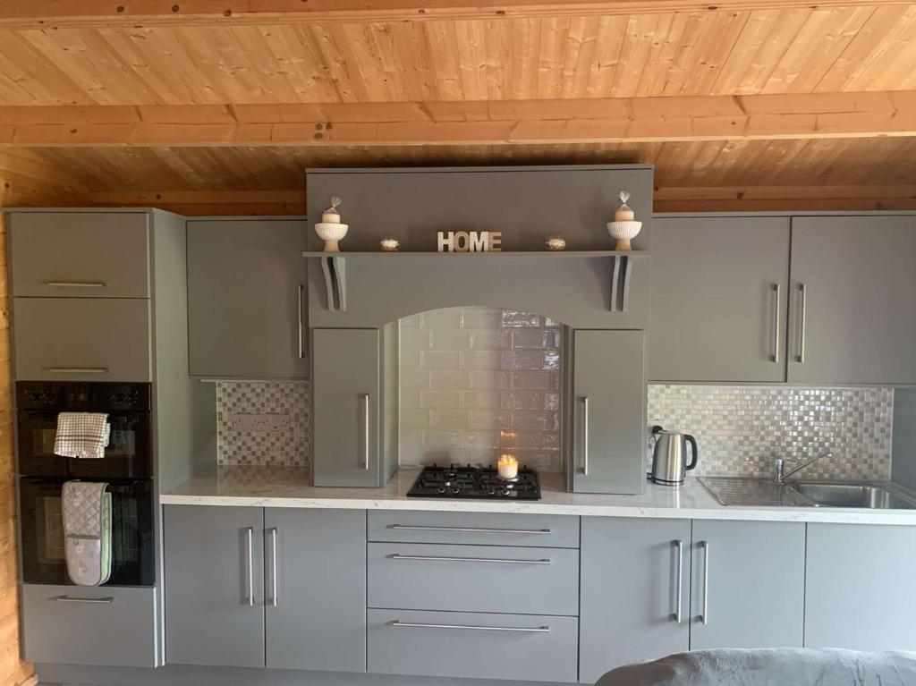 a kitchen with white cabinets and a stove top oven at Cheerful Cozy Cabin in Countryside in Limerick