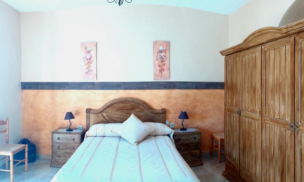 1 dormitorio con 1 cama grande y cabecero de madera en La Plazuela, casa andaluza con patio., en Montoro