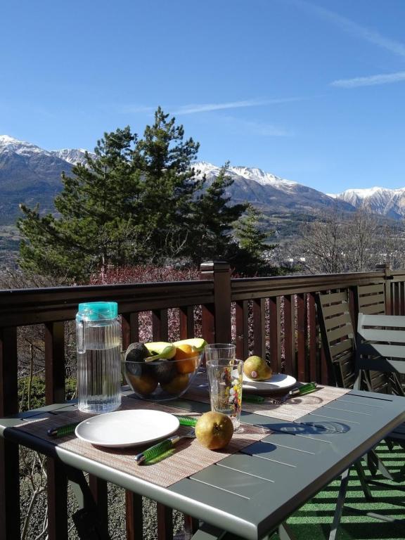 einen Tisch mit Obstteller auf dem Deck in der Unterkunft EMBRUN Superbe appartement classé 3 étoiles tout équipé avec vue sur montagnes in Saint-Sauveur