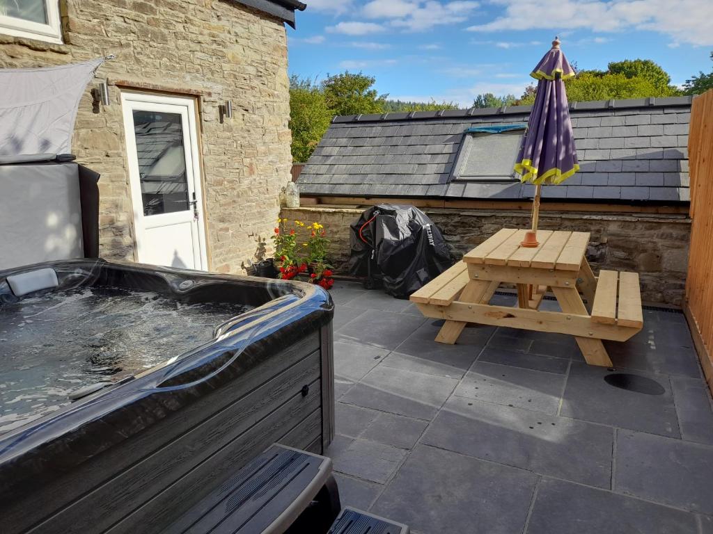 a hot tub and a picnic table with an umbrella at Fig Cottage Holiday Home in Whitecroft
