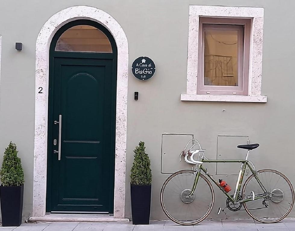 uma bicicleta estacionada em frente a um edifício com uma porta verde em A Casa di BiaGio em Rapolano Terme