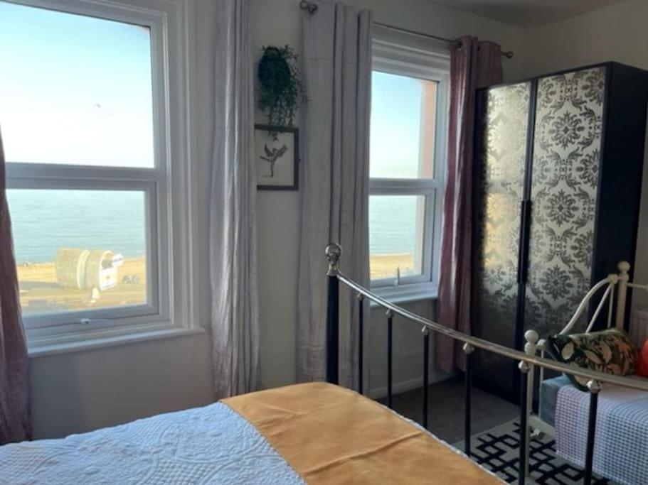 um quarto com uma cama e duas janelas em "The Quirky" Seafront Apartment em Eastbourne
