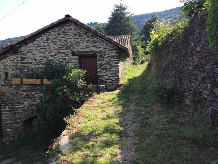 un edificio in pietra con una porta sul fianco di una collina di Maison rurale au cœur des Cévennes Ardéchoises a Dompnac