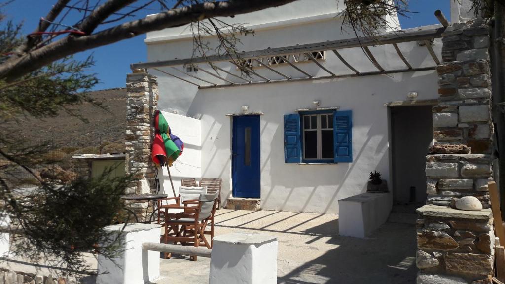ein weißes Haus mit blauen Türen und einem Regenschirm in der Unterkunft home on the AGAPIANI sea in Kollimpithra