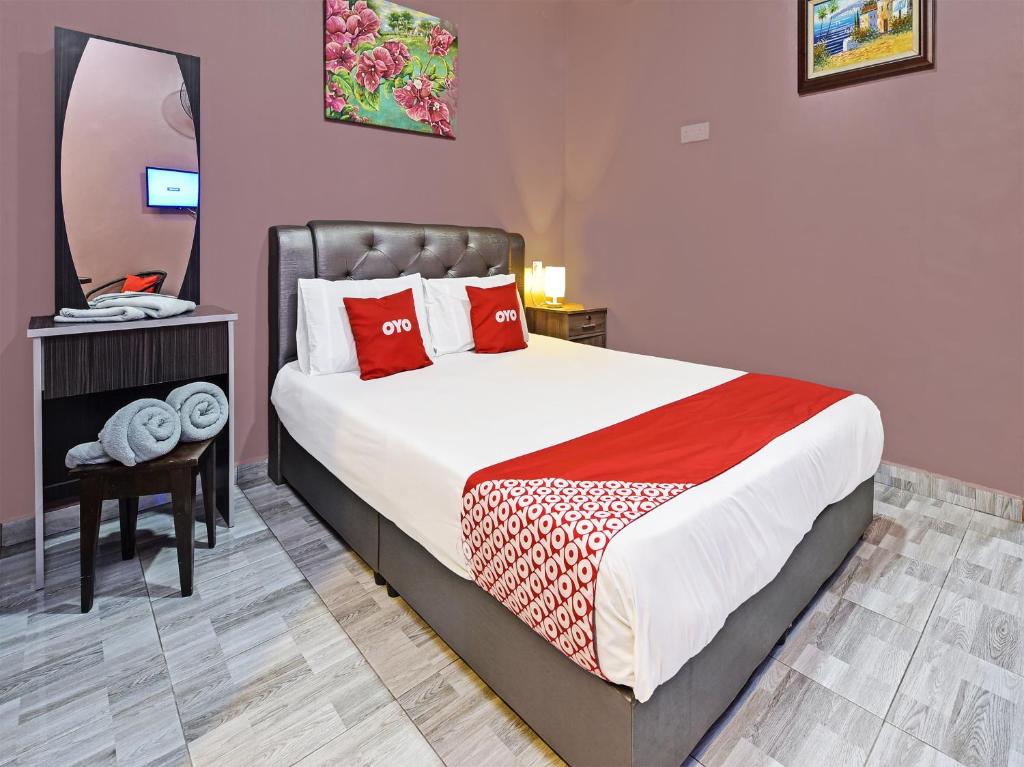 OYO Home 90348 Inspire Rooms في بانتايْ سينانج: غرفة نوم بسرير ومخدات حمراء ومرآة