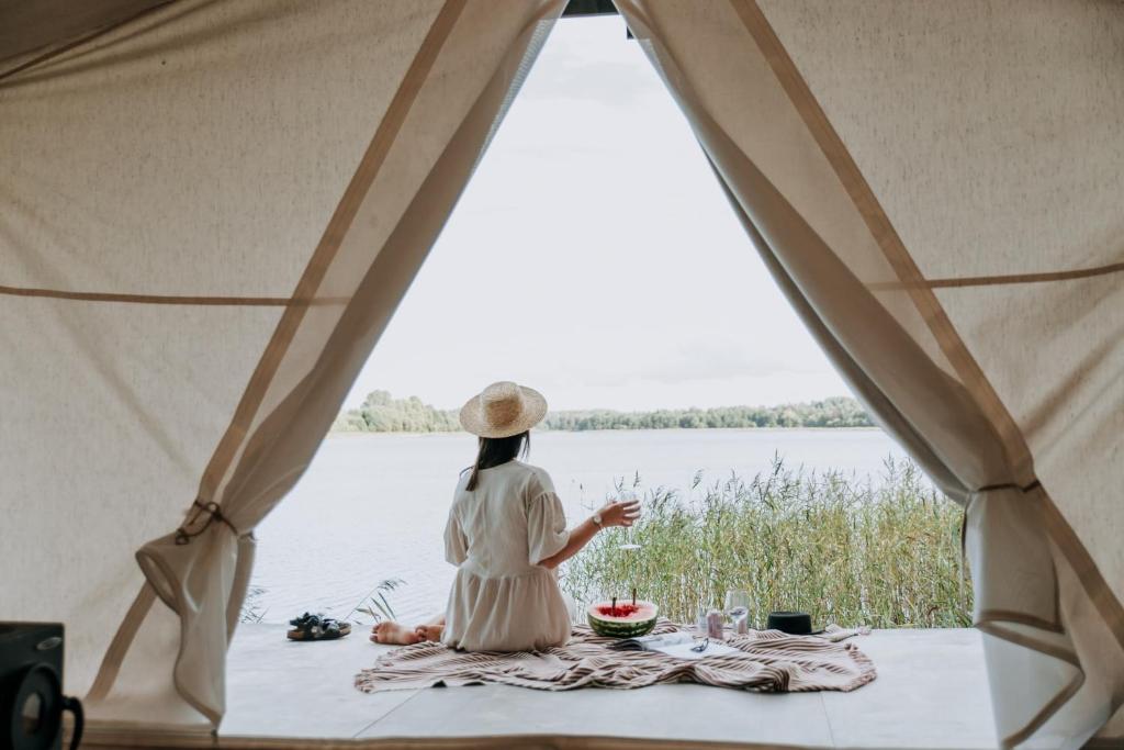 Tykkimäki Resort في كووفولا: امرأة جالسة في خيمة تطل على الماء
