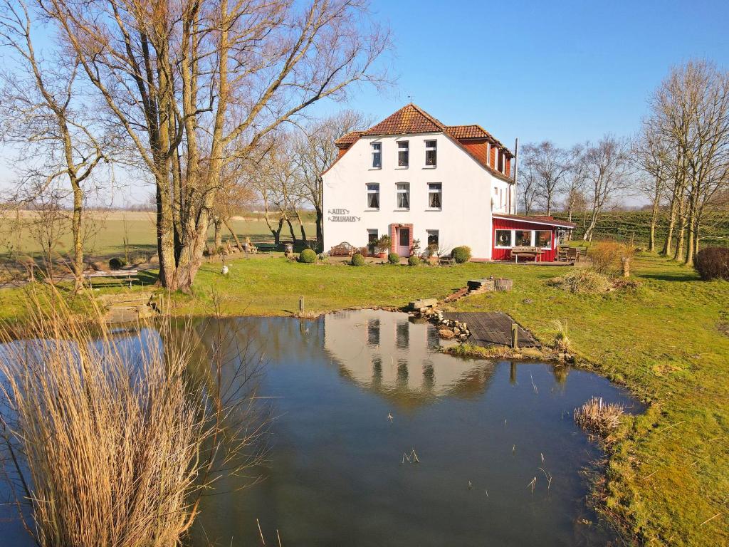 a large white house with a pond in front of it at Pension Altes Zollhaus in Norden