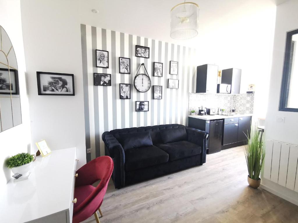 sala de estar con sofá negro y cocina en Dieppe, Studio cosy front de mer en Dieppe