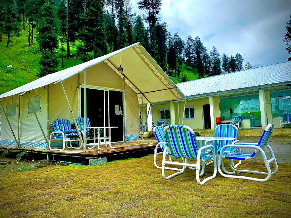 four chairs and a table in front of a house at Valhalla Resort Kumrat in Tāl
