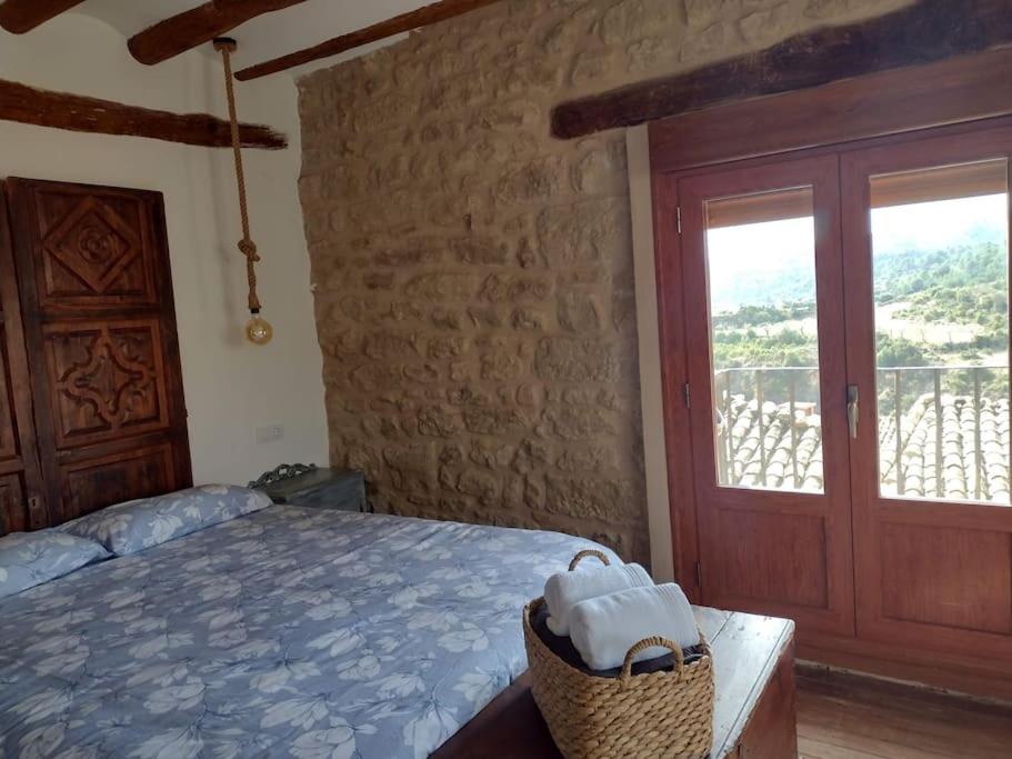 1 dormitorio con cama, ventana y puerta en El Desván del Campanero apartamento con jardín, en Murillo de Gállego