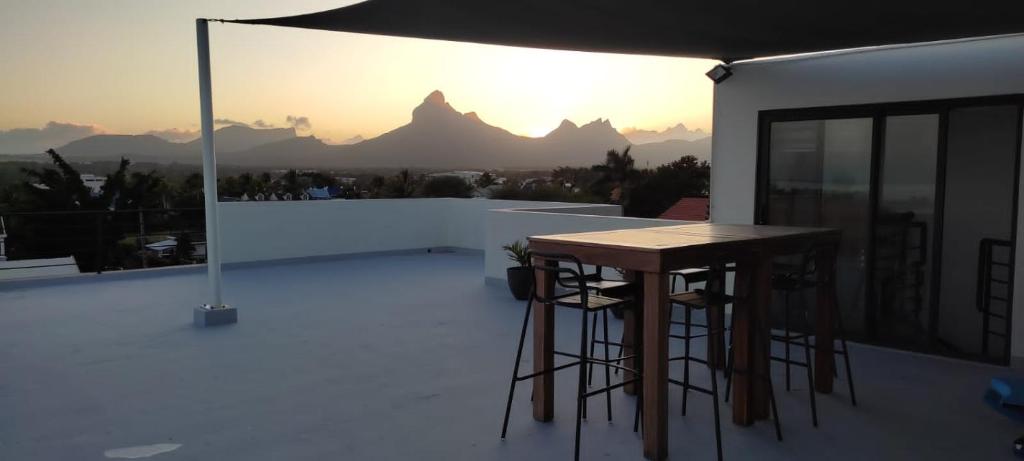 une table et des tabourets sur le toit d'une maison dans l'établissement Superbe appartement avec vue mer et montagnes., à Tamarin