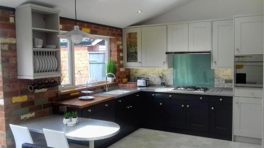 a kitchen with white cabinets and a table and a sink at Stunning & Spacious Family Home. Midlands location in Coventry