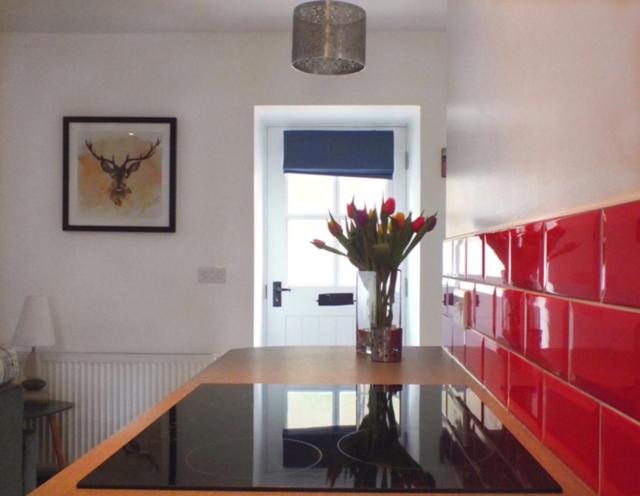 a vase of flowers on a glass table in a room at Boggle Dyke Cottage in Thornhill