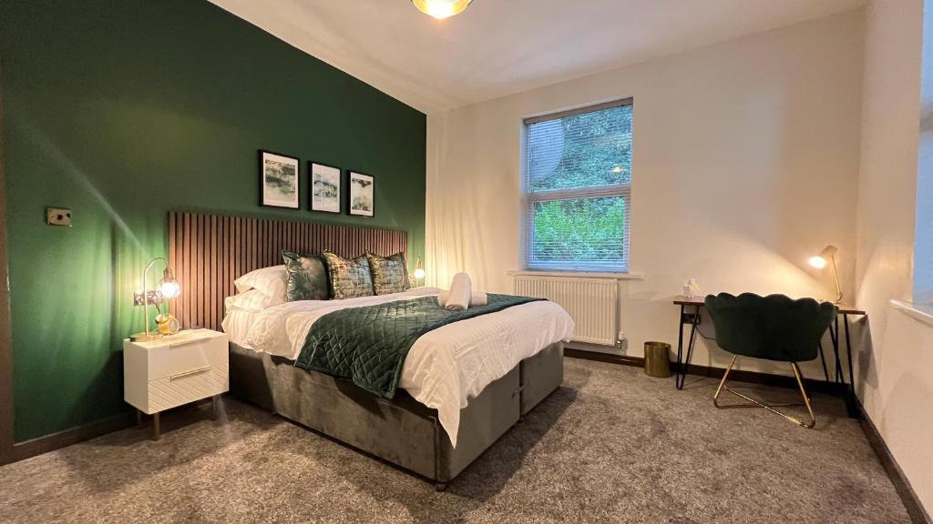 a bedroom with green walls and a bed and a chair at Canalside in Headingley