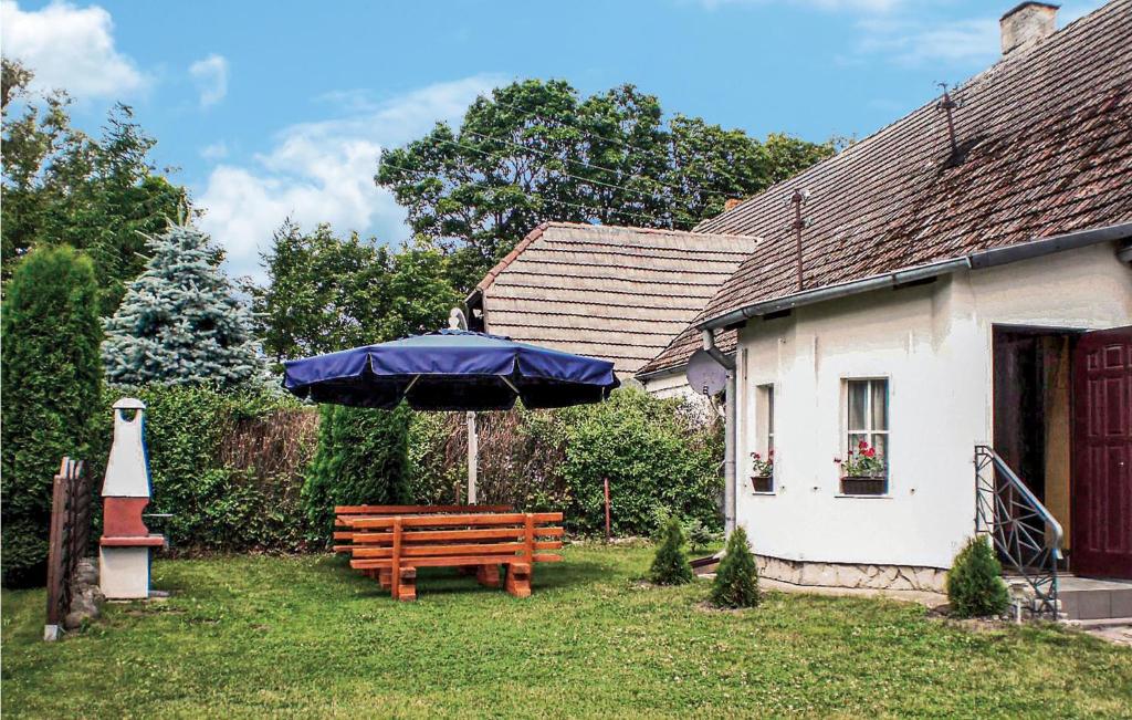 a wooden bench with a blue umbrella in a yard at 2 Bedroom Stunning Apartment In Retowo 4 in Gardna Wielka