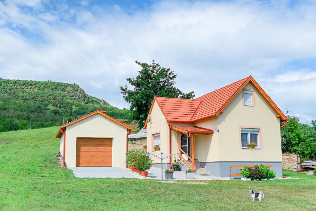 una casa con techo rojo en un campo verde en Bazaltorgona Apartman, en Kisapáti
