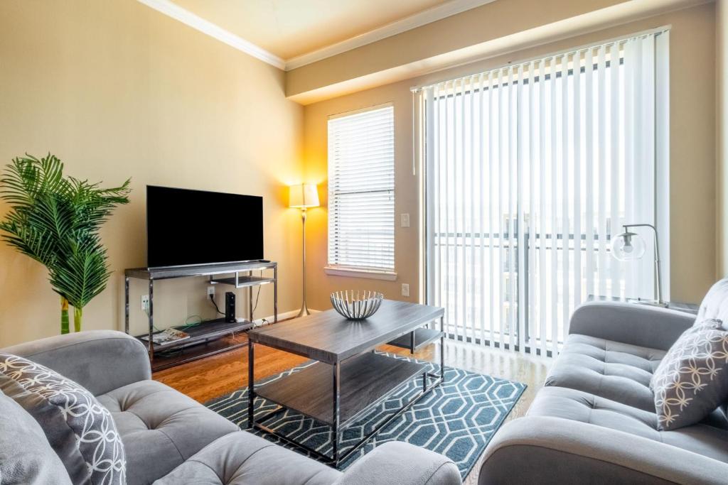 a living room with two couches and a tv at 2BR Executive Suite With Pool, Gym and Fast Wi-Fi By ENVITAE in Dallas