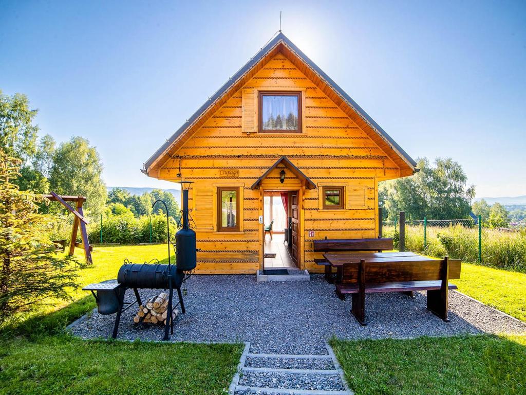 a small wooden cabin with a bench and a table at Domki pod Bieniatka w Szczyrku in Szczyrk