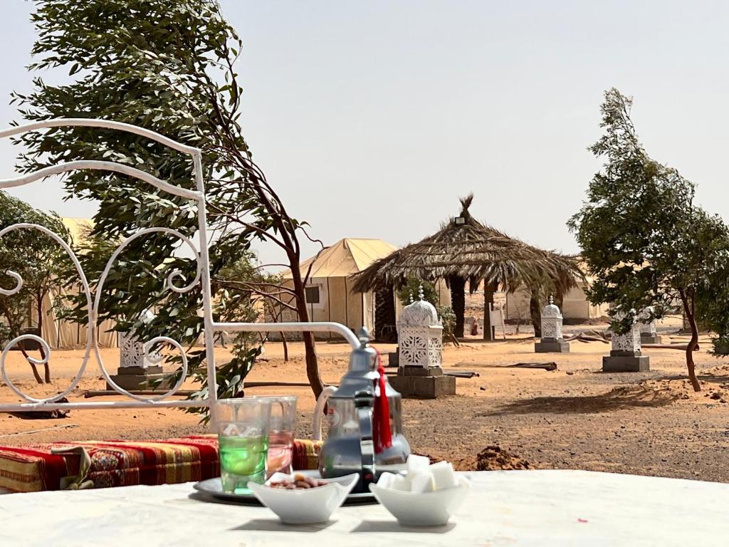 een tafel met een drankje en kommen eten erop bij Merzouga Camp & Desert Activities in Merzouga