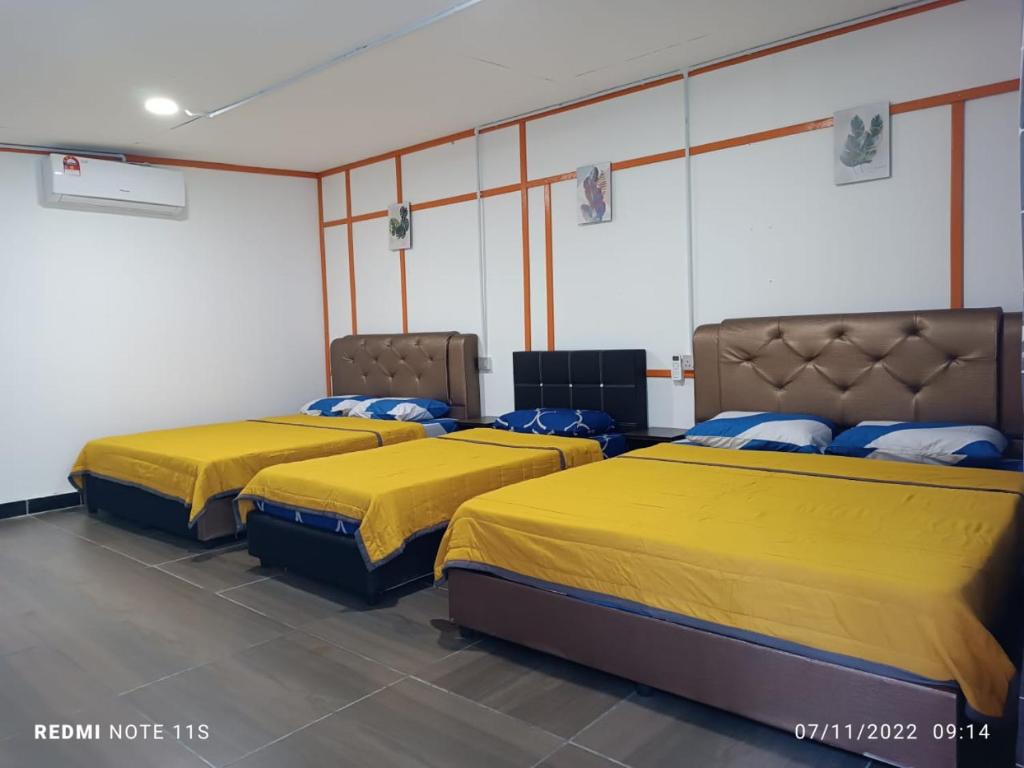 two beds in a room with yellow sheets at Juara Ocean Chalet in Kampong Juara