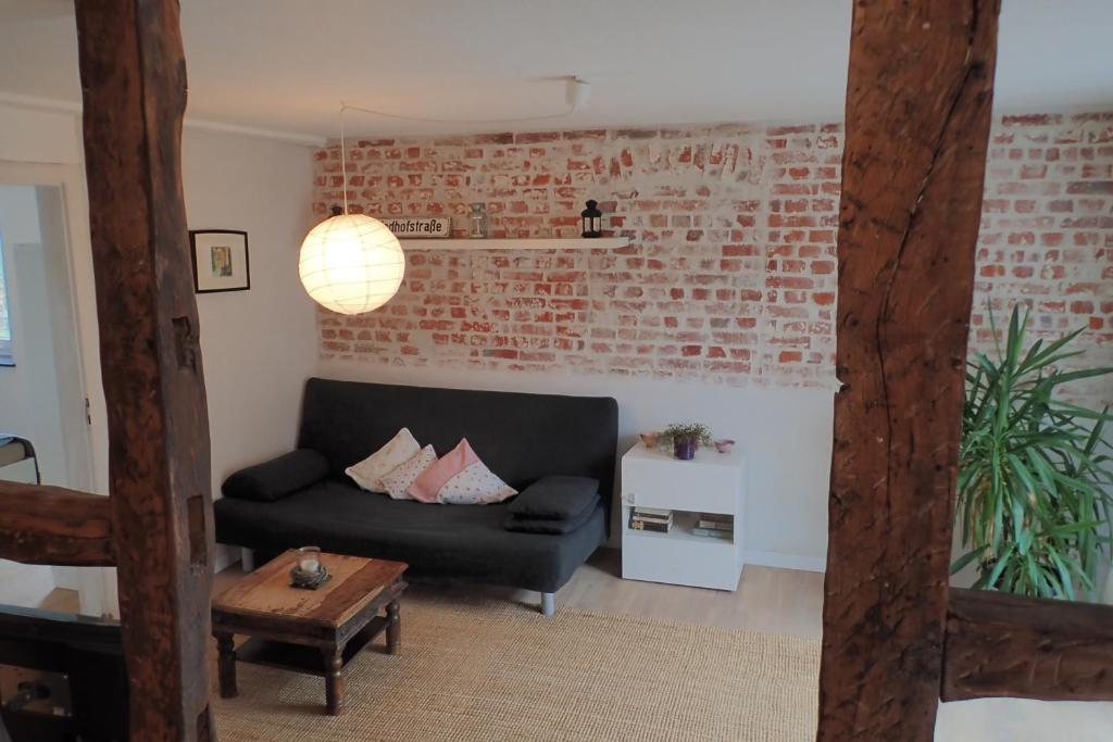 a living room with a black couch and a brick wall at Ferienwohnung Holzmaden Am Platz in Holzmaden